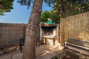 a stone fireplace next to a bench next to a tree at Villetta Simius in Villasimius
