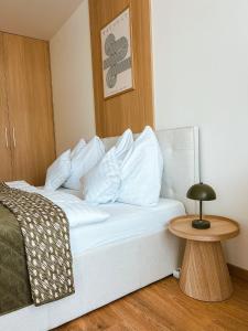 a bed with white pillows and a table in a room at Bloom Olive Apartment in Trenčín