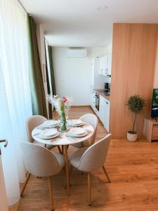 a table with chairs and a vase of flowers on it at Bloom Olive Apartment in Trenčín