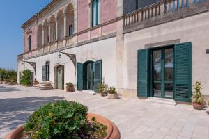 a building with green doors and plants in a courtyard at Villa Minioti Apartment A in Arnesano