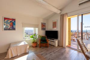 a living room with a television and a balcony at Gîte Durance Mallemort in Mallemort