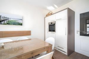a dining room with a wooden table and white cabinets at Haus Seezeit in Malchow