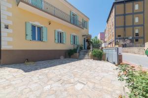 a building with green shuttered windows and a stone driveway at Maison Chloe in La Maddalena