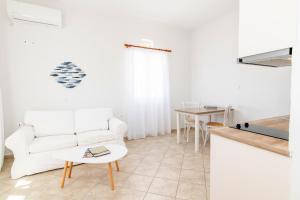 a living room with a white couch and a table at Anemologio 102 Tinos in Agios Ioannis