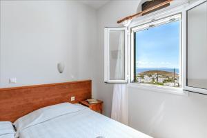 a bedroom with a bed and a large window at Anemologio 102 Tinos in Agios Ioannis