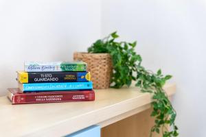 a stack of books on a shelf with a plant at Bilocale Valledoria in Valledoria