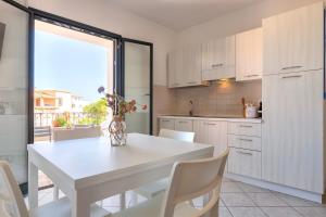 a white kitchen with a white table and chairs at Bilocale Valledoria in Valledoria