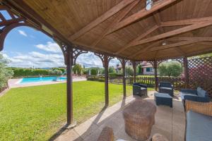 an outdoor pavilion with a table and chairs and a pool at Tenuta Vallegaia in Rosignano Marittimo