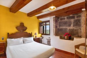 a bedroom with a white bed and a yellow wall at Casamira in Sagás +36 photos