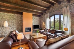 a living room with leather furniture and a stone wall at Casamira in Sagás