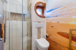 a bathroom with a toilet and a painting of the beach at Moin Moin in Friedrichskoog-Spitze +29 photos