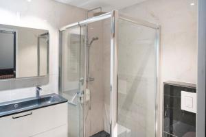 a bathroom with a glass shower and a sink at Villa Patio Proche Plage in Seignosse
