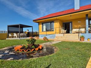 a yellow house with a tree in the yard at Villa Laurana in Suances