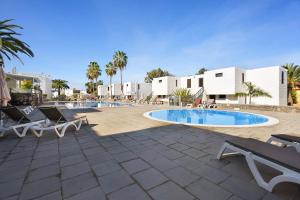 a swimming pool with lounge chairs and a resort at Bungamerica272 in Playa de las Americas