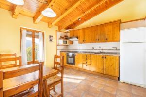 a kitchen with wooden cabinets and a table and a refrigerator at Jaumet 2 Sant Martí de Barcedana in Aransís