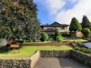 a house with a stone wall in front of a yard at Zur schönen Aussicht in Schotten +7 photos
