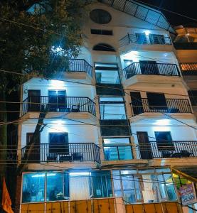 a tall white building with windows and balconies at night at The Plaza Dalhousie - Near Ghandhi Chowk Mall Road in Dalhousie