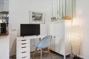 a room with a desk with a tv and a blue chair at Landhaus Peenemünde - Garten in Peenemünde