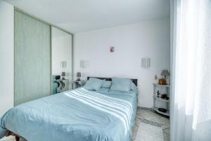 a white bedroom with a large bed with blue pillows at Chez Anne Marie Et Daniel in Gardouch