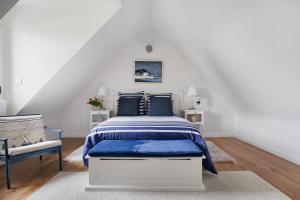 a white bedroom with a blue bed and a chair at Chambres D'hôtes Les Goélands in Saint-Cast-le-Guildo