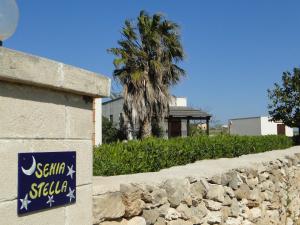 a sign on a stone wall next to a palm tree at Isola Di Favignana in Favignana
