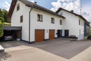a white house with a car garage at Ferienwohnung Christa in Lennestadt