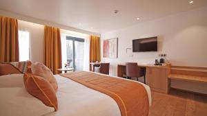 a hotel room with a bed and a desk and a television at Hotel Le Charme de la Semois in Alle