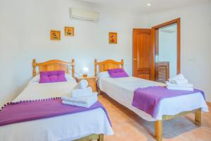 two beds in a room with purple and white sheets at Finca Can Cocou in Can Picafort +26 photos
