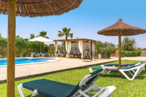 a pool with two chairs and an umbrella at Finca Can Cocou in Can Picafort