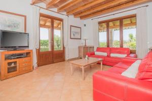a living room with red furniture and a flat screen tv at Finca Can Cocou in Can Picafort