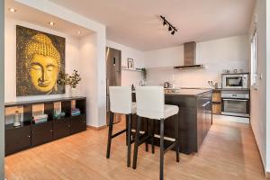 a kitchen with a bar with white chairs and a painting at Almijarahouse in Nerja