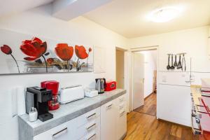 a kitchen with white cabinets and red flowers on the wall at Tapas Restaurante 2 in Viersen +15 photos