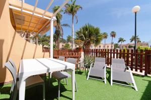 a white table and chairs on a lawn with palm trees at Oasis Pool View in Maspalomas