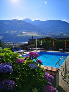 a pool with purple flowers and mountains in the background at Kleon 2 in Rifiano