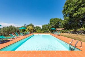 a swimming pool with blue chairs and umbrellas at Agriturismo Paugnano in Radicondoli