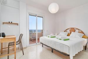 a white bedroom with a bed and a desk and a window at Casa Bellota in Torrox +25 photos
