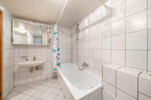 a white bathroom with a tub and a sink at Bungalow 41 - Kimbucht in Reichendorf +21 photos