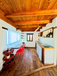 a kitchen with wooden ceilings and a table with red chairs at La gloria nature & relax in Puerto del Rosario