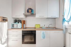 a kitchen with white cabinets and a sink and a microwave at Linda's Pet Friendly Beach House in Rapallo