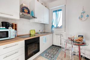 a kitchen with white cabinets and a table and a microwave at Linda's Pet Friendly Beach House in Rapallo +30 photos