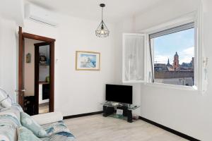a white living room with a tv and a window at Linda's Pet Friendly Beach House in Rapallo