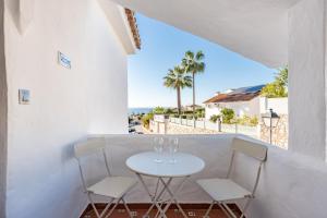a table with two wine glasses on a balcony with the beach at Apartment Mijas Sun and Beach in Sitio de Calahonda