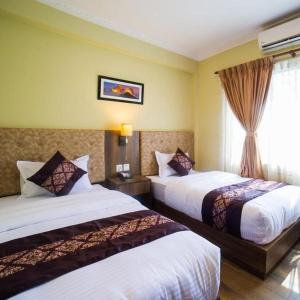 a hotel room with two beds and a window at Hotel Thakali Inn in Kathmandu