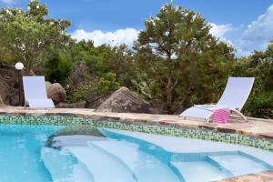 a swimming pool with two lawn chairs and a swimming pool at Nido in Monte Petrosu