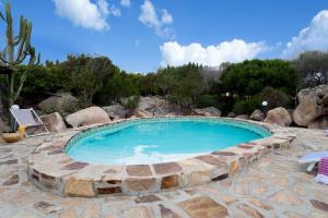a large swimming pool in a patio with rocks at Nido in Monte Petrosu