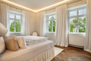 a white bedroom with windows and a bed at Schloss Kirchberg -Appartment Fleur in Immenstaad am Bodensee
