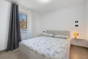 a white bedroom with a large bed and a window at Cà De Qualì in Costa Volpino