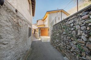 an alley with a stone wall next to a building at Cà De Qualì in Costa Volpino