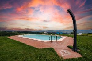 a swimming pool in a field with a sunset at Appartamento Lavanda in Radicofani