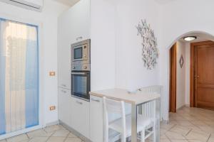 a kitchen with white walls and a table with chairs at Appartamento Murena 1 in La Maddalena +17 photos